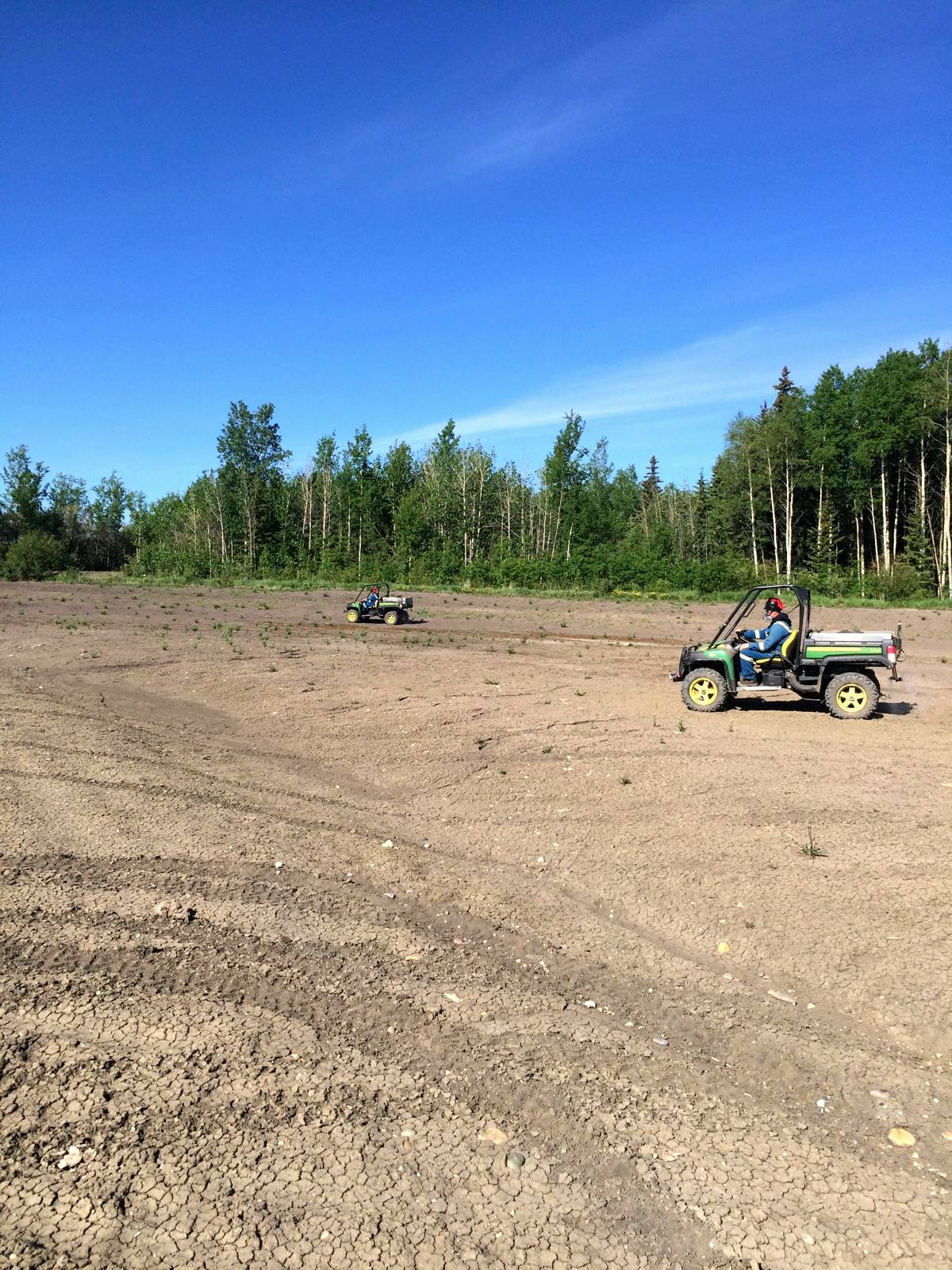 Two side-by-sides crossing a reclaimed lease surface during a weed control pass