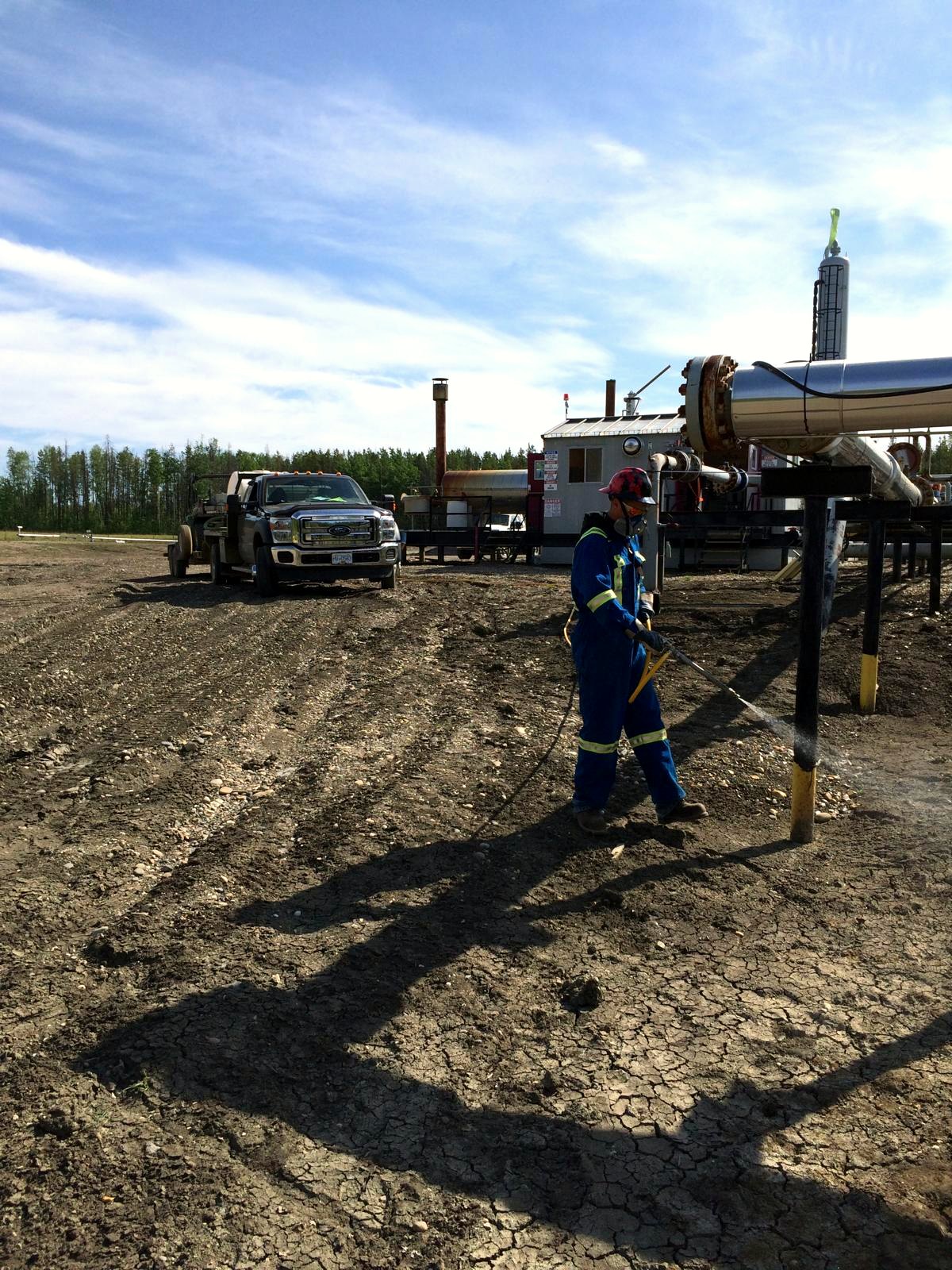 Applicator spraying around pipeline supports at a gas facility