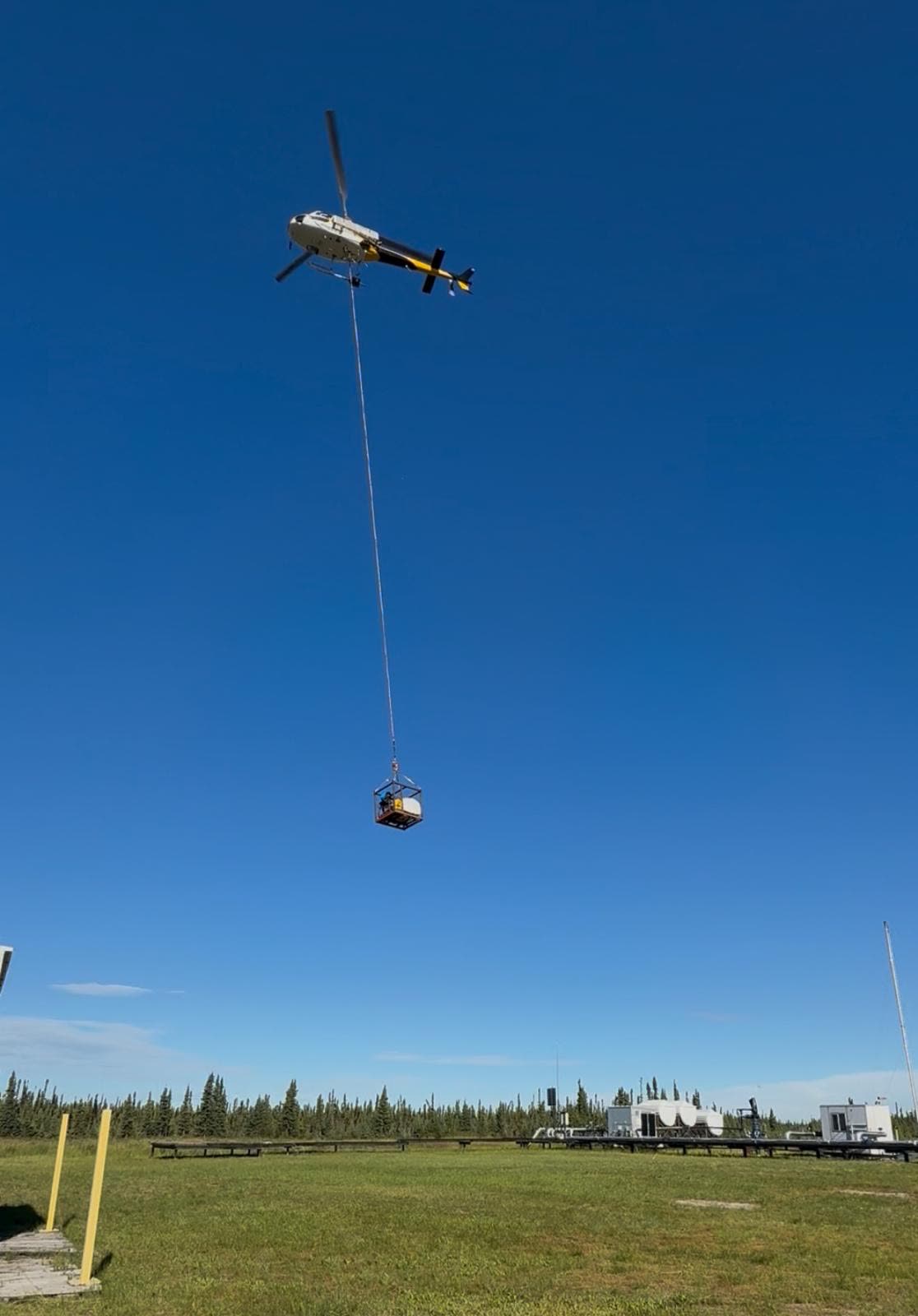 Helicopter carrying a sling load of equipment into a remote cutline in Northeast BC